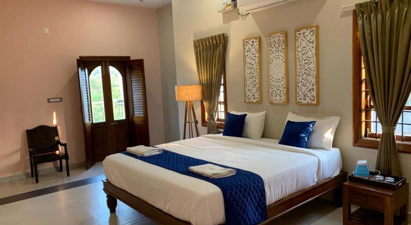 Deluxe Villa bedroom with a king bed and tall arched louvered doors onto the greenery