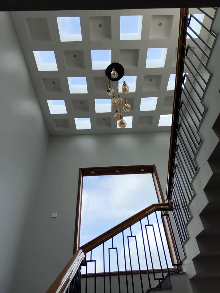 Double-height stairwell with a coffered skylight ceiling and hanging pendant lights